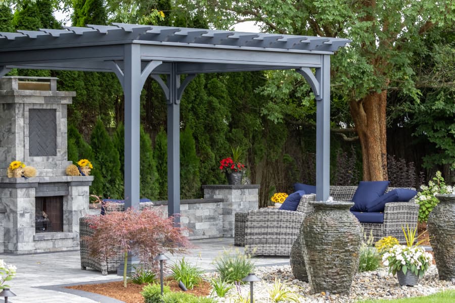 Pergola covering outdoor stone fireplace and chairs